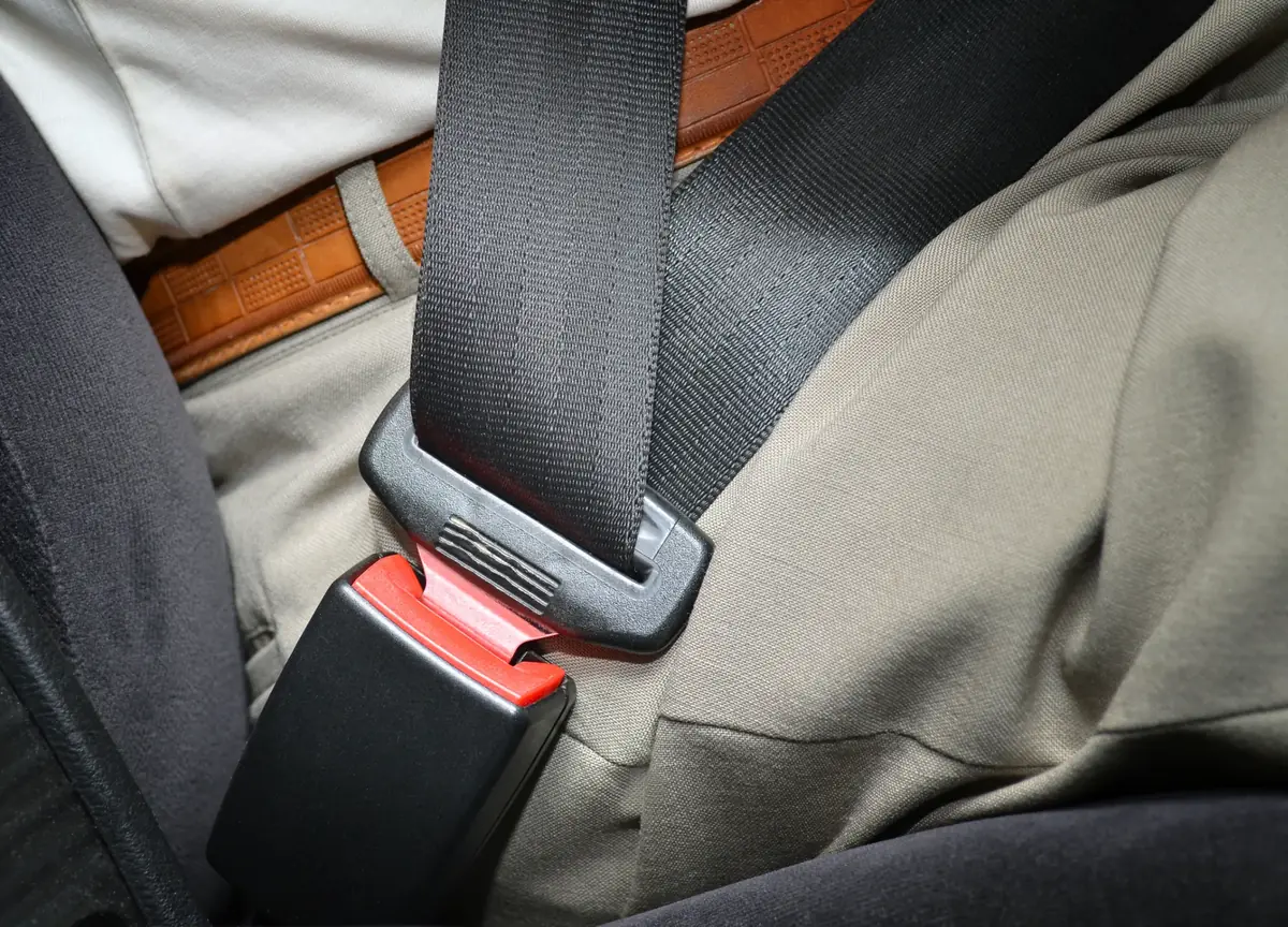 Seat belt fastened across the hips of a seated occupant in a vehicle with fabric upholstery